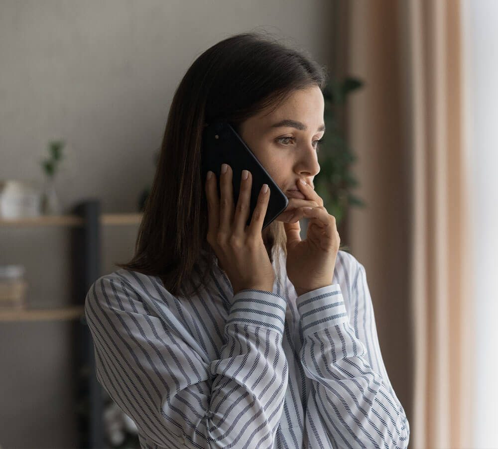 Sad millennial woman has difficult phone talk hold gadget by ear listen to unexpected bad news think on answer.