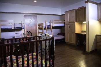 client bedroom with bunk beds, a crib and personal desk and storage cabinet